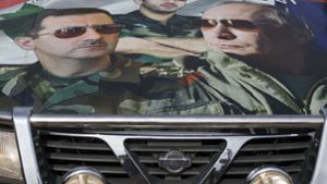 Eine Collage mit dem russischen Diktator Baschar al-Assad (links) und Russlands Präsident Wladimir Putin auf der Motorhaube eines Autos in Syrien. Foto: AP