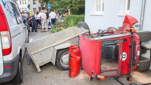 Ein Kleintraktor mit Anhänger liegt am Samstag nach einem Unfall neben einer Hauswand in Bad Camberg. Bei dem Unfall sind der Fahrer und 13 Kinder teils schwer verletzt worden. Foto: dpa