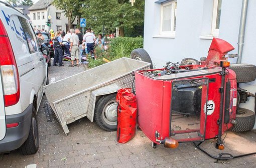 Ein Kleintraktor mit Anhänger liegt am Samstag nach einem Unfall neben einer Hauswand in Bad Camberg. Bei dem Unfall sind der Fahrer und 13 Kinder teils schwer verletzt worden. Foto: dpa