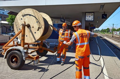 Fachkräfte des Bautrupps rollen  Kabel von einer großen Trommel. Foto: Eva Schäfer