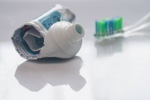 Bild von einer leeren Zahnpastatube mit Zahnbürste im Hintergrund.