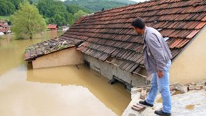 Ein Mann blickt vom Dach seines Hauses auf die überflutete Straße in Pozega, 200 Kilometer süd-westlich von Belgrad. Foto: dpa