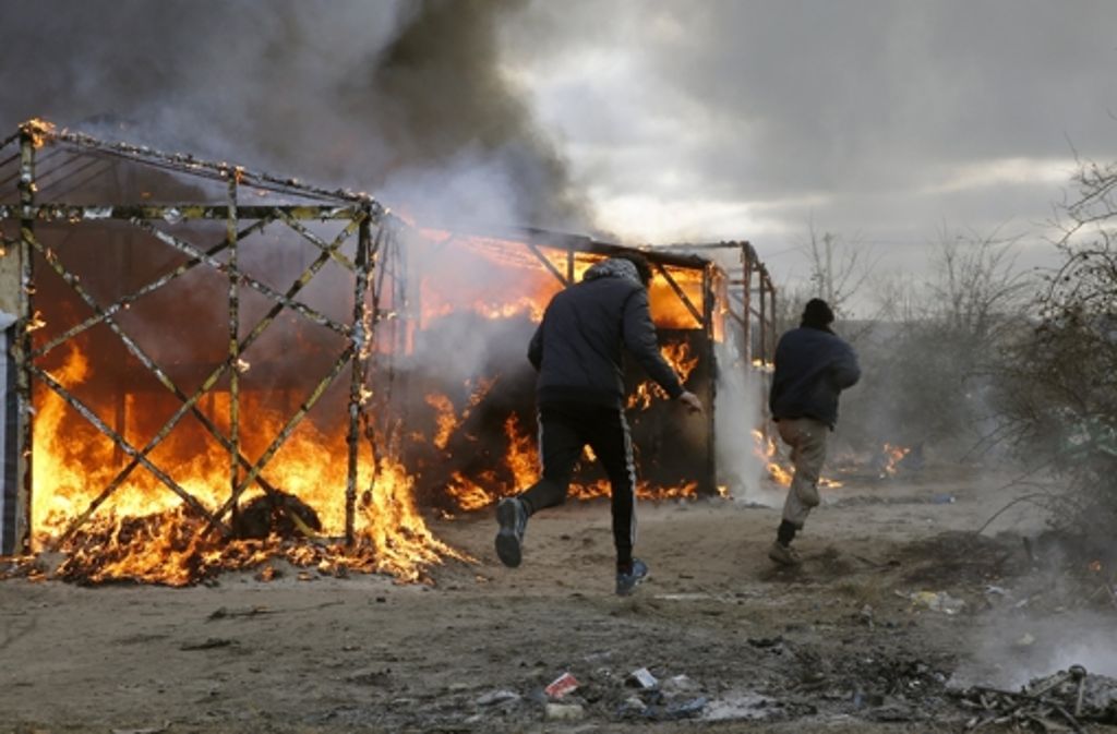 Flüchtlinge rennen an den brennenden Zelten vorbei.