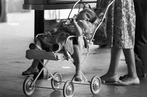 Eine Mutter steht am 22.07.1963 auf dem Frankfurter Hauptbahnhof neben dem Kinderwagen, in dem ihr schlafender Sohn und seine kleinere Schwester liegen. Die von der CDU in den Koalitionsverhandlungen mit der SPD geforderte bessere Mütterrente für Frauen, deren Kinder vor 1992 geboren wurden, würde mit 6,5 Milliarden Euro zu Buche schlagen. Foto: dpa