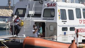 Sanitäter tragen Kinder von Bord eines Schiffes der italienischen Küstenwache. Die Flüchtlinge hatten auf  zwei Rettungsschiffen vor Italien ausgeharrt. Foto: ANSA/AP