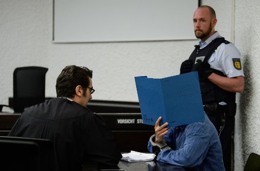 Der Angeklagte (links sein Verteidiger Nenad Mikec) verbirgt sein Gesicht. Foto: dpa