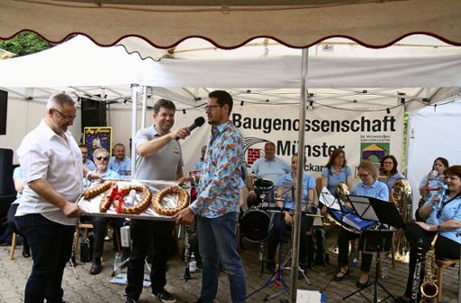 Markus Kassner und Jörg Sailer (rechts) überbringen den Jubiläumszopf des Handels- und Gewerbevereins Münster, Stefan Sendelbach (Mitte)  hält das Mikro für die Gratulation für den Bäckermeister bereit. Foto:  