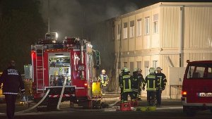 Feuerwehrleute vor der brennenden  Flüchtlingsunterkunft in Rottenburg am Neckar. Foto: dpa