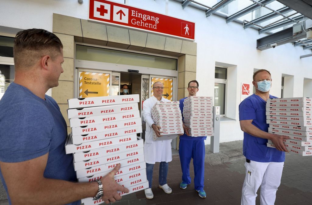 Klinik-Mitarbeiter nehmen die Pizzen in Empfang. Foto: factum/Simon Granville