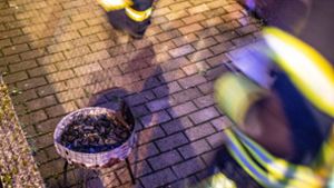 Feuerwehrleute bringen den Holzkohlegrill nach draußen, der zu einer tödlichen Gefahr wurde. Foto: 7aktuell.de/Simon Adomat