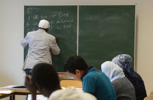 Ein Flüchtling übt im Deutschkurs an der Tafel Verben zu beugen. Foto: dpa