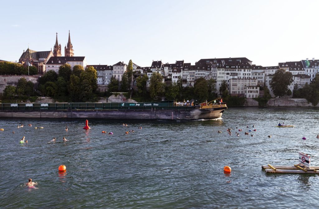 Rhein-Schwimmer in Basel genießen das Stadtpanorama vom Wasser aus. Man lässt sich flussabwärts treiben, Kleidung und Handy hat man in einer wasserfesten Tasche, einem sogenannten Wickelfisch, dabei.