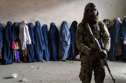 Ein Taliban-Kämpfer steht in Kabul Wache, während Frauen darauf warten, von einer Hilfsorganisation Lebensmittel zu erhalten. Foto: dpa/Ebrahim Noroozi