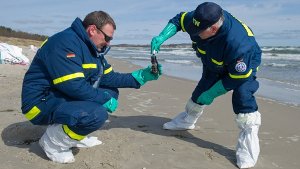 Helfer sammeln auf Rügen die Ölklumpen ein. Foto: dpa