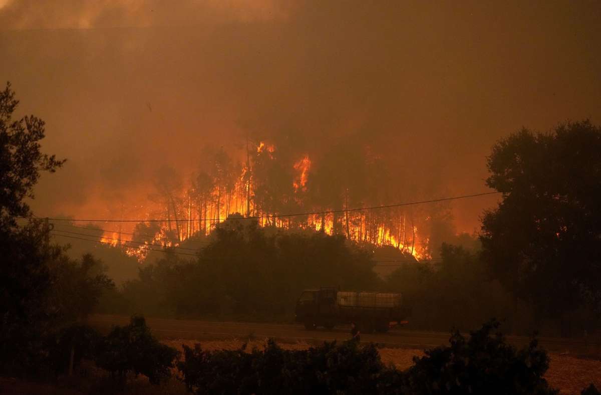 Ein Lastwagen mit Wassertanks fährt an einem Waldbrand vorbei, während Rauch den Himmel im Dorf Bemposta in der Nähe von Ansiao verdunkelt.