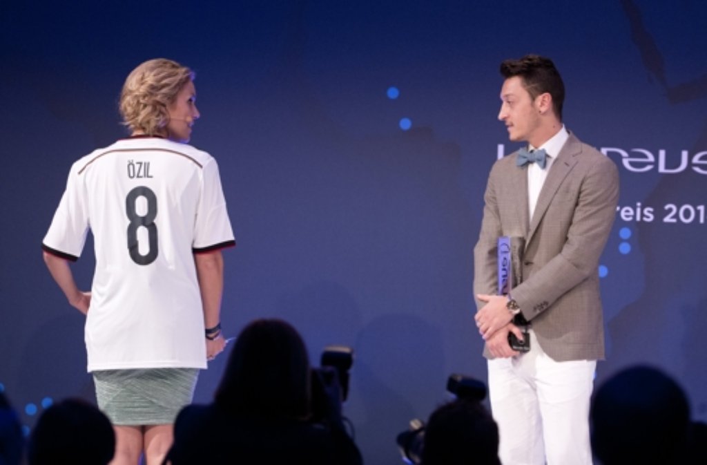 Fußballer Mesut Özil hat den Ehrenpreis für Wohltätigkeit bei der Verleihung des Laureus Medien Preises von der Moderatorin Kathi Wörndl überreicht bekommen. Foto: dpa