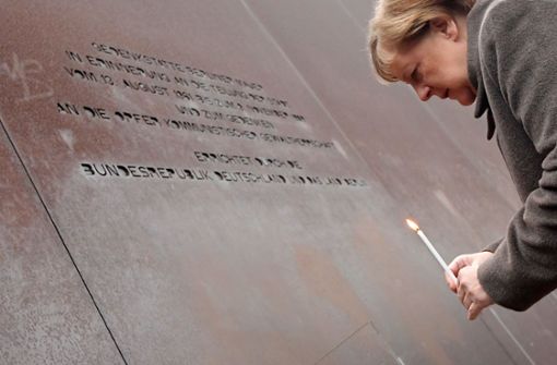 Angela Merkel mit Kerze an der Gedenkstätte Berliner Mauer. Foto: AFP/TOBIAS SCHWARZ