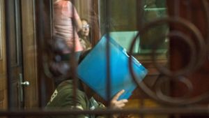 Der Angeklagte versteckt im Gerichtssaal sein Gesicht hinter einem Ordner. Foto: AFP