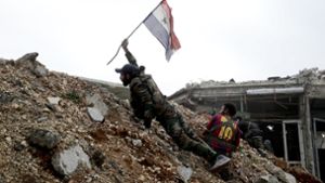 Ein Soldat der syrischen Armee hält eine Nationalflagge seines Landes in Ost-Aleppo hoch. Foto: AP