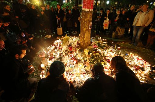 Trauernde Menschen zünden am 16.11.2015 vor dem Bataclan in Paris (Frankreich) Kerzen an und legen Blumen nieder (Archivbild). Foto: dpa