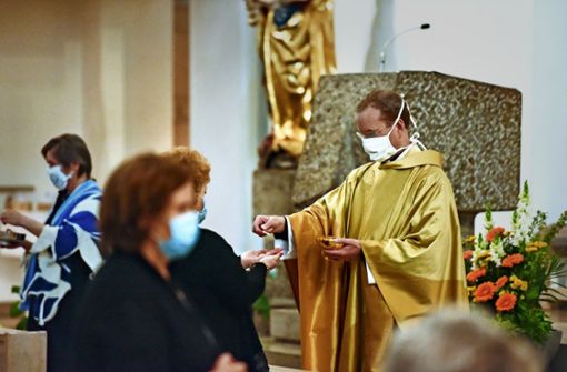 Der Stuttgarter Stadtdekan Christian Hermes verteilt in der Messe die Hostien mit einer Pinzette. Foto: Lichtgut/Max Kovalenko