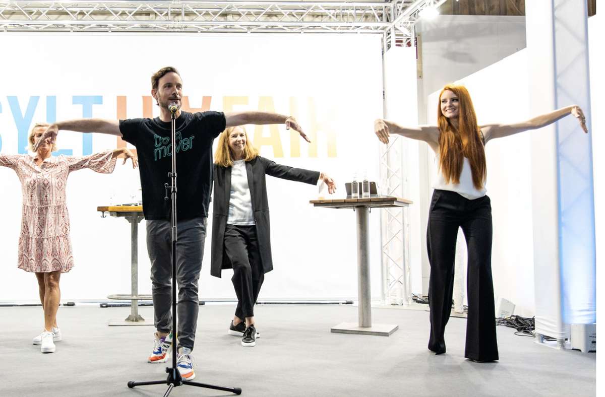 Eric Gauthier (am Mikrofon) übt bei der Sylt Art Fair mit Promis, darunter  Model und Schauspielerin Barbara Meier (rechts), den Schwanentanz ein.