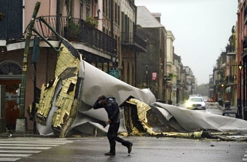 New Orleans am Sonntag : Ein Mann geht an einem Teil des Daches vorbei, das durch den Hurrikan Ida von einem Gebäude im French Quarter weggeblasen wurde Foto: dpa/Eric Gay