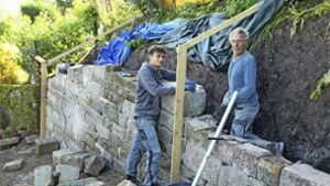 Spezialisten bauen die eingestürzte Trockenmauer wieder auf. Foto: Martin Dolde