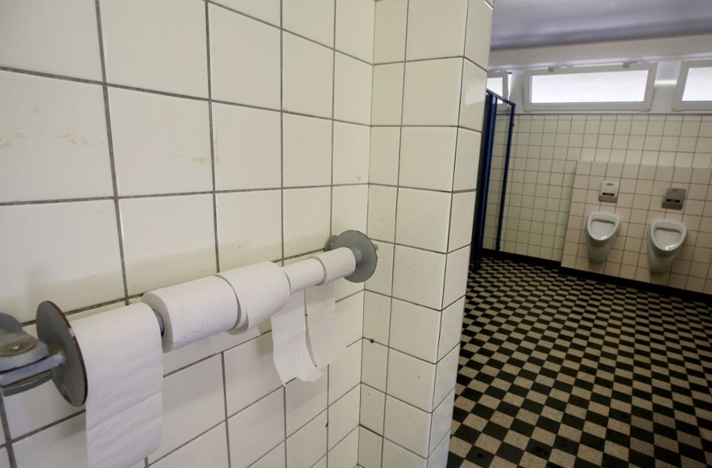 Mit einem Hängeschloss gesicherte Toilettenpapierrollen hängen in einer noch nicht renovierten Toilette einer Grundschule im nordrhein-westfälischen Duisburg.