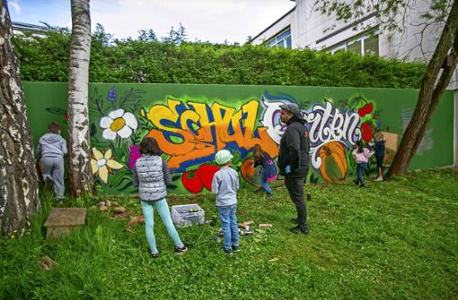 Gökhan Rizov und die Kinder gestalten die Wand des Schulgartens. Foto: Roberto Bulgrin