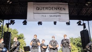 Berlin: Polizisten stehen bei einer  Kundgebung gegen die Corona-Beschränkungen auf der Straße des 17. Juni auf der Bühne unter einem Transparent der Initiative “Querdenken 711“. Foto: dpa/Christoph Soeder