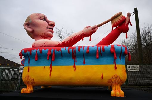 Wladimir Putin nimmt ein Blutbad – in einer Badewanne in den ukrainischen Landesfarben. Ein Umzugswagen steht für den Rosenmontagsumzug in Düsseldorf bereit. Foto: dpa/Federico Gambarini