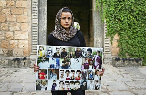 Die in den Irak zurückgekehrte Aschwak T. hält ein Porträt von IS-Opfern aus ihrem Heimatdorf in den Händen. Foto: AFP