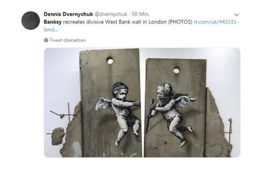 Banksy präsentiert ein Mauerstück mit einem Graffiti auf einer Reisemesse in London. Foto: screenshot/@dvernychuk