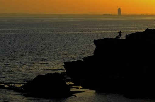 Zypern, Ayia Napa: Touristen genießen den Sonnenuntergang bei den Meereshöhlen im südlichen Küstenort Ayia Napa im Südosten der Mittelmeerinsel Zypern. Foto: Tom Jennings/AP/dpa/Tom Jennings