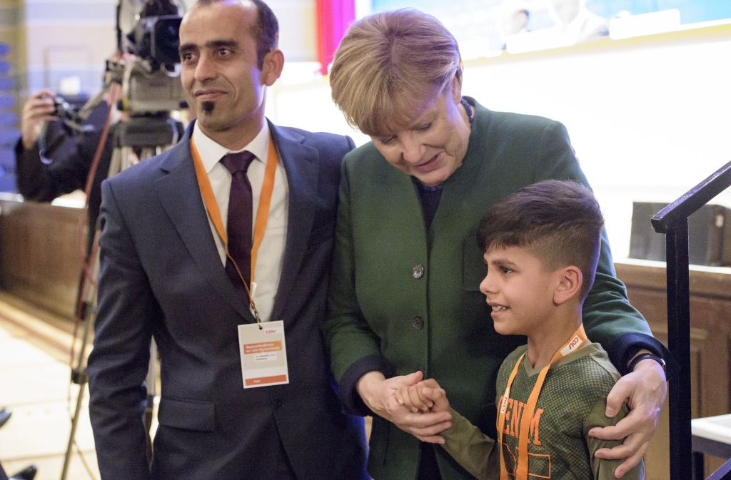 Merkel mit einem afganischen Flüchtlingsjungen auf der CDU-Regionalkonferenz in Heidelberg: Viele Bürger haben inzwischen die Nase voll von solchen Szenen Foto: dpa