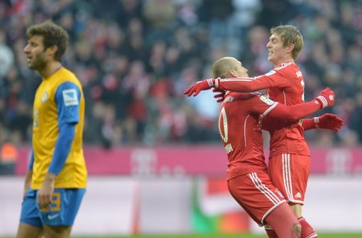 Arjen Robben (Mitte) und Toni Kroos von Bayern München jubeln über das Tor zum 2:0, während Marco Caligiuri (links) von Braunschweig enttäuscht ist.  Foto: dpa