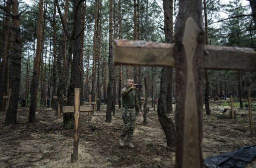 Nach der Rückeroberung in der Stadt Isjum. Ein Mann filmt mit seinem Smartphone die nicht identifizierten Gräber von Zivilisten und ukrainischen Soldaten. Foto: dpa/Evgeniy Maloletka