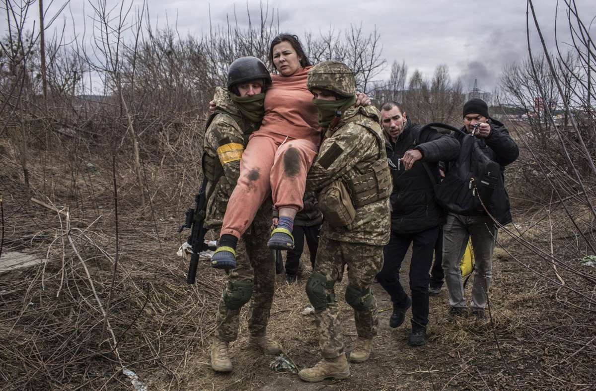 Eine Frau wird bei der Flucht aus der Stadt Irpin von ukrainischen Soldaten getragen.