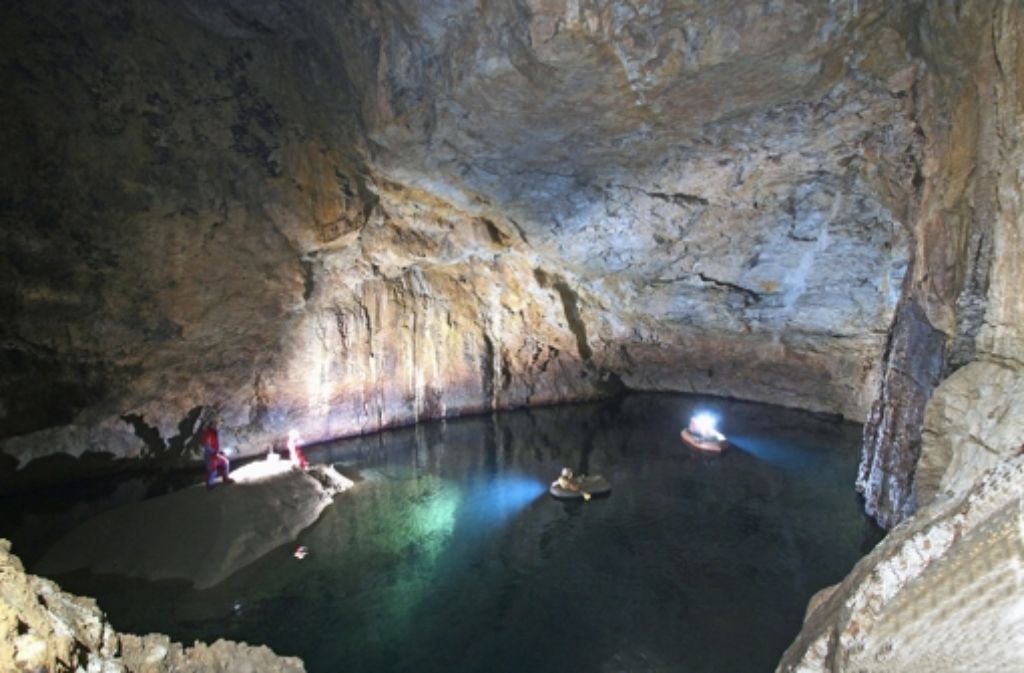 In einem kleinen Schlauchboot paddeln die Speläologen auf dem See im Wolkenschloss. Hinten rechts führt ein Weg unter Wasser in die Blauhöhle.