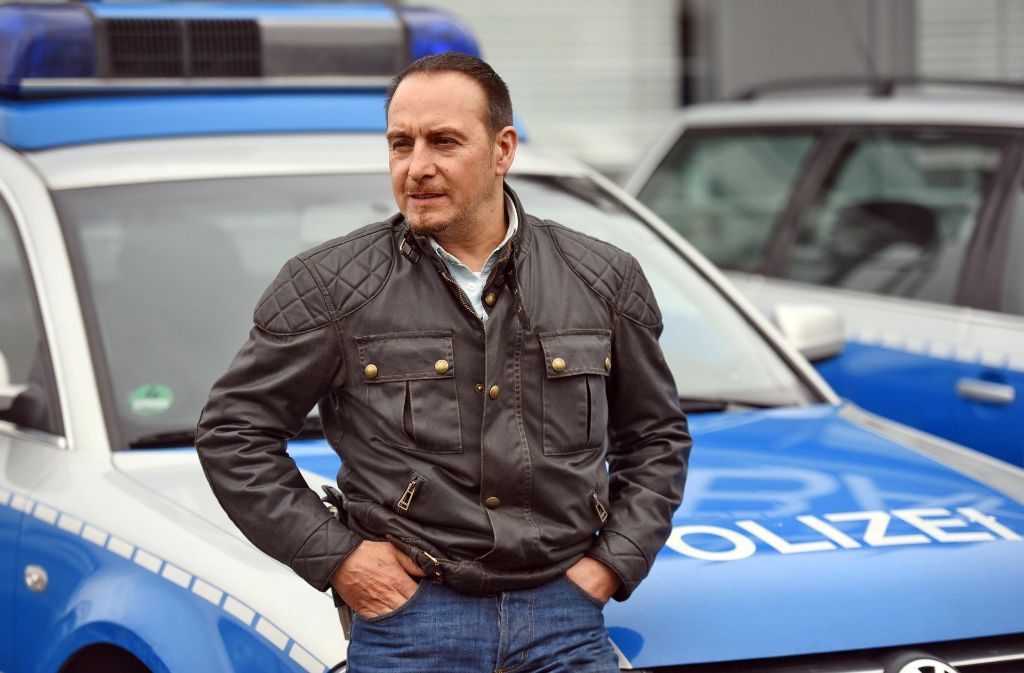 Der Schauspieler Erdogan Atalay sitzt am  in Hürth (Nordrhein-Westfalen) bei einem Fototermin am Rande von Dreharbeiten zur RTL-Serie „Alarm für Cobra 11“ auf der Motorhaube eine Polizeiautos. Foto: dpa