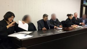 Die drei Angeklagten (gepixelt) beim Prozessauftakt in Stuttgart mit ihren Anwälten. Foto: dpa