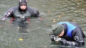 Polizisten in Neoprenanzügen suchen in Augsburg im Eiskanal nach Spuren der Mörder. Foto: dpa