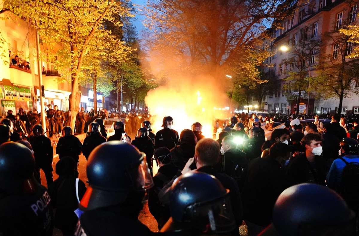 Polizisten stehen am Rande der Demonstration linker und linksradikaler Gruppen unter dem Motto „Demonstration zum revolutionären 1. Mai“ vor einem Feuer auf der Straße.