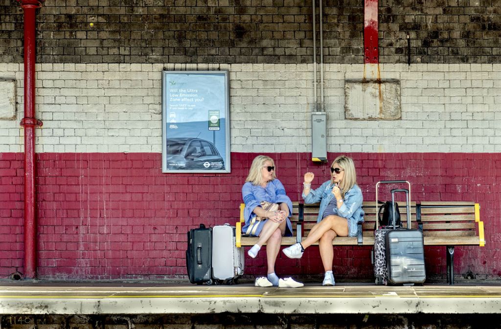 Erst mal die Schuhe aus: zwei Frauen in London überbrücken die Wartezeit – vermutlich an einer U-Bahnstation – mit Reden.