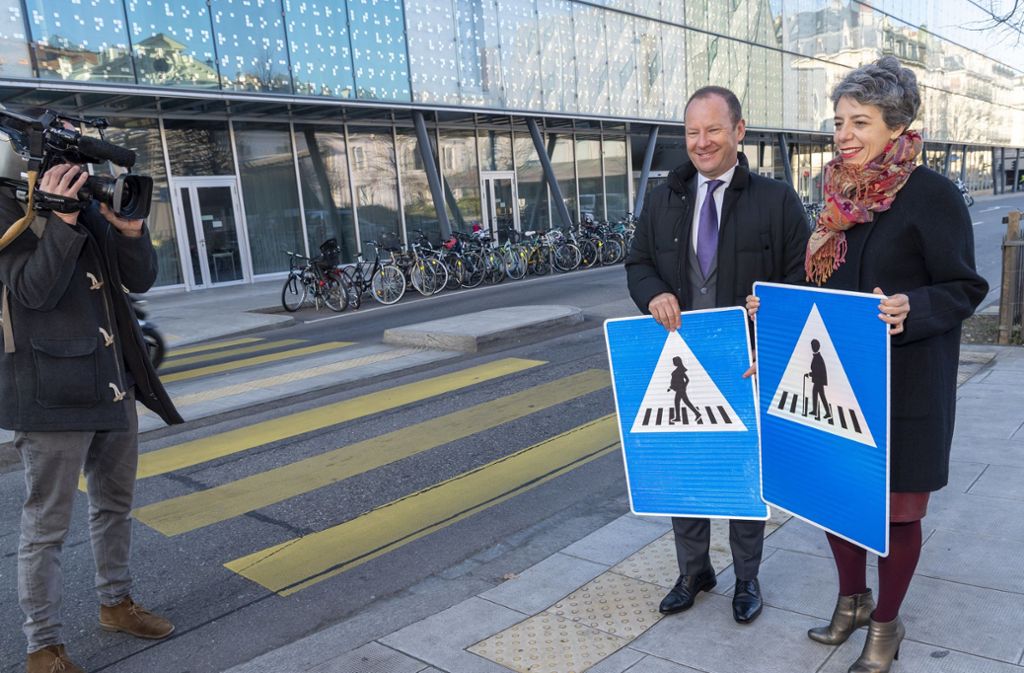 Die Genfer Stadtpräsidentin Sandrine Salerno (re.) und Serge Dal Busco, zuständiger Staatsrat für Infrastruktur, stellen neue Verkehrsschilder an einem Zebrastreifen vor.  Insgesamt sollen 250 Schilder mit den sechs neuen Variationen aufgehangen werden.
