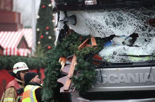 Ein Polizist und ein Feuerwehrmann stehen am 20.12.2016 in Berlin vor einem beschädigten LKW. Bei einem möglichen Anschlag war ein Unbekannter tags zuvor  mit einem Lastwagen auf einen Weihnachtsmarkt an der Berliner Gedächtniskirche gefahren. Foto: dpa