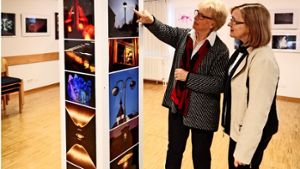 Eine schlanke Säule für viele Hochformate: Ursula Plocher (links) und Birgit Wauro haben aktiv an der Ausstellung „Faszination Licht“ mitgearbeitet. Foto: factum/Granville