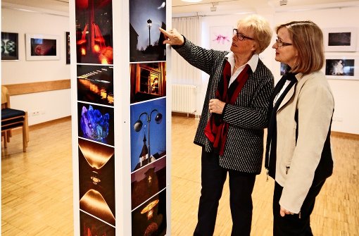 Eine schlanke Säule für viele Hochformate: Ursula Plocher (links) und Birgit Wauro haben aktiv an der Ausstellung „Faszination Licht“ mitgearbeitet. Foto: factum/Granville