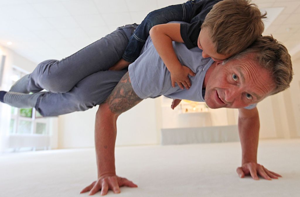Rama Schwab macht mit seinem  Sohn Christoffer die Krähe, eine Yoga-Pose.